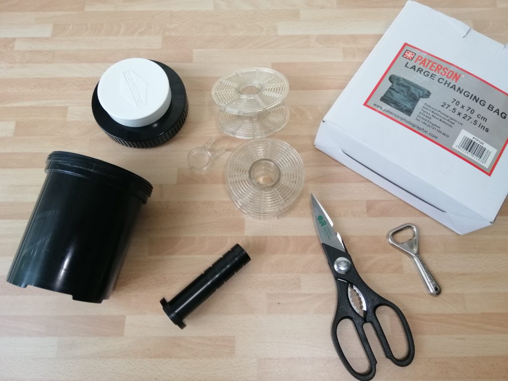 Entwicklertank, Wechselsack, Schere und Flaschenöffner. Wichtiges Zubehör für die Filmentwicklung.